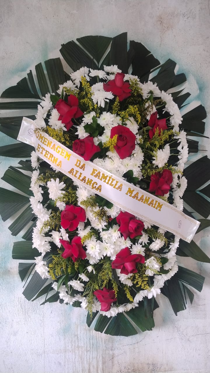 coroa de flores com rosas vermelhas, crisântemos brancos e folhas de palmeira com fita dourada, sobre fundo cl